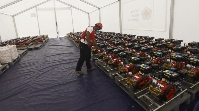 Petugas Palang Merah Indonesia (PMI) meninjau logistik kesehatan di Gudang Logistik Darurat Penanganan  virus Corona COVID-19 di Jalan Gatot Soebroto, Jakarta, Rabu (25/3).  [Suara.com/Angga Budhiyanto]  