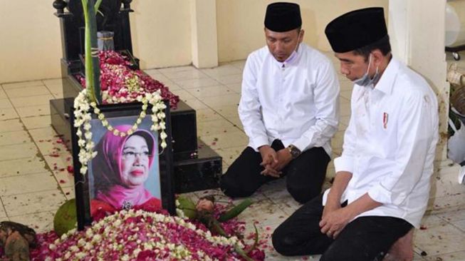 Presiden Joko Widodo memandang foto almarhumah ibundanya Sujiatmi Notomiharjo  di TPU Mundu, Kelurahan Selokaton, Kecamatan Gendangrejo, Kabupaten Karanganyar, Solo,  Kamis (26/3). [Foto/Agus suparto]