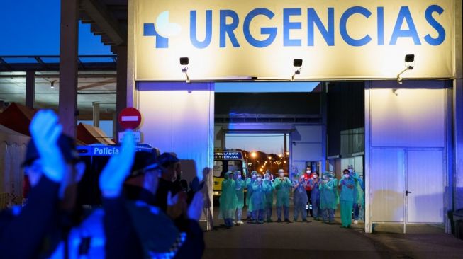 Para petugas medis keluar dari sebuah rumah sakit di Burgos, Spanyol dan diberi semangat oleh orang-orang di tengah wabah virus corona yang melanda. (Foto: AFP / Cesar Manso)