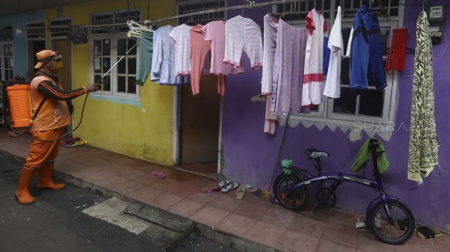 Petugas melakukan penyemprotan cairan disinfektan di rumah warga Gang Haji Sairan, Kelurahan Jati Padang, Pasar Minggu, Jakarta Selatan, Kamis (26/3). [Suara.com/Angga Budhiyanto]