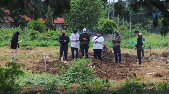 Pelayat melakukan shalat jenazah kepada jenazah pasien suspect Corona di TPU Tegal Alur, Jakarta Barat, Kamis (26/3). [Suara.com/Alfian Winanto]