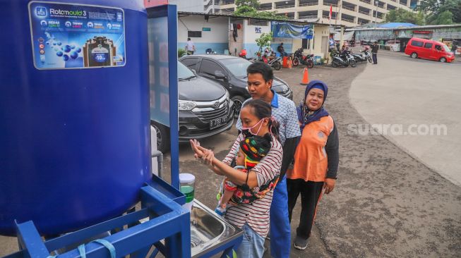 Warga mengantre untuk mencuci tangan di Wastafel Portable agar terhindar dari virus di Terminal Depok, Jawa Barat, Sabtu (28/3). [Suara.com/Alfian Winanto]