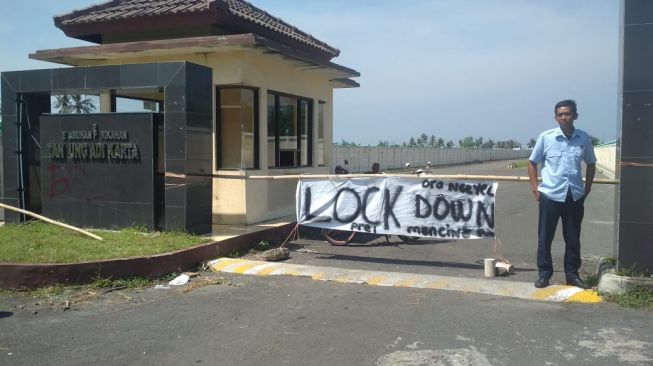 Petugas keamanan Pelabuhan Tanjung Adikarta sedang bertugas menjaga pintu masuk pelabuhan setelah dilakukan lockdown mandiri, Minggu (29/3/2020). - (SuaraJogja.id/Hiskia Andika)