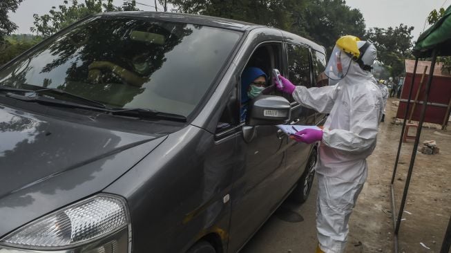 Petugas Dinas Kesehatan Kota Depok memeriksa suhu pengendra mobil saat tes cepat (rapid test) pendektesian COVID-19 dengan sistem "drive-thru" di Cimanggis, Depok, Jawa Barat, Minggu (29/3). [ANTARA FOTO/Muhammad Adimaja]