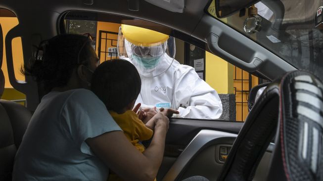 Petugas Dinas Kesehatan Kota Depok melakukan pengecekan kepada pengguna kendaraan saat tes cepat (rapid test) COVID-19 dengan sistem "drive thru" di Cimanggis, Depok, Jawa Barat, Minggu (29/3). [ANTARA FOTO/Muhammad Adimaja]