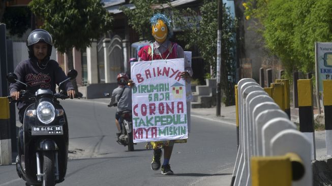 Seorang pria berkeliling sambil mengenakan topeng dan membawa sejumlah imbauan guna mengajak masyarakat membantu penanganan virus Corona (COVID-19) di Palu, Sulawesi Tengah, Minggu (29/3). [ANTARA FOTO/Mohamad Hamzah]