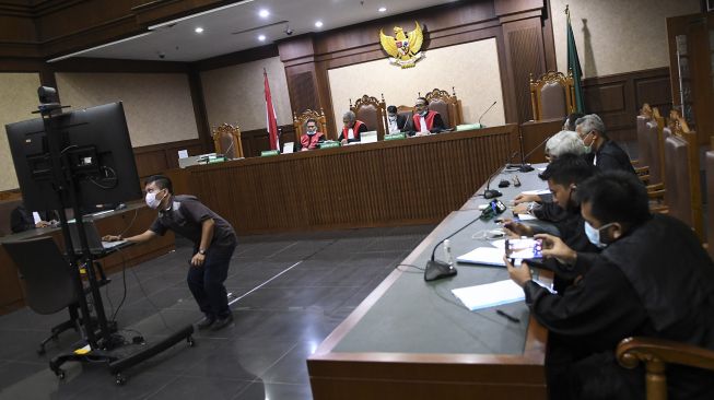 Suasana jalannya sidang putusan kasus korupsi proyek peningkatan jalan Kemiri-Depapre tahun 2015 berjalan dengan berbasis elektronik secara langsung (telekonferensi) di Pengadilan Tipikor, Jakarta, Senin (30/3). [ANTARA FOTO/M Risyal Hidayat]