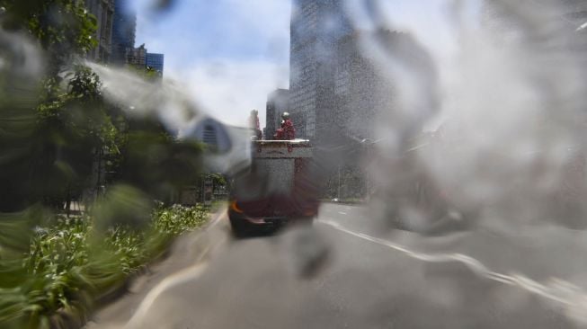 Petugas menyemprotkan cairan disinfektan di sepanjang jalan Jenderal Sudirman-MH Thamrin, Jakarta, Selasa (31/3).  [ANTARA FOTO/Muhammad Adimaja]