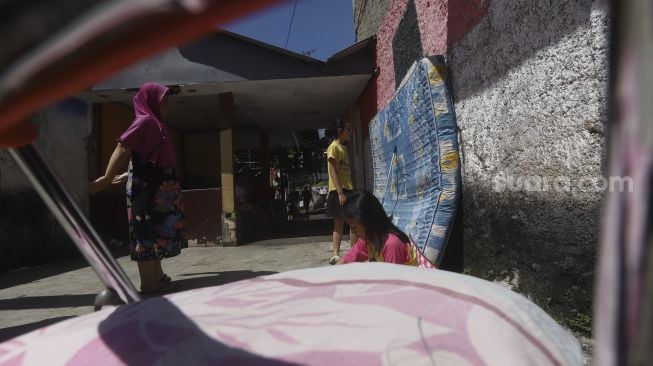 Sejumlah warga berjemur sambil melakukan olahraga ringan di bawah sinar matahari pagi di Gang Haji Sairan, Kelurahan Jati Padang, Pasar Minggu, Jakarta Selatan, Selasa (31/1). [Suara.com/Angga Budhiyanto]