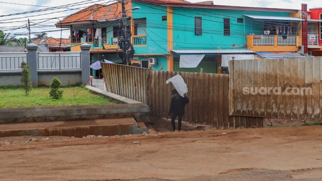 Warga beraktivitas didepan jalan yang ditutup seng di RW 04 Cipinang Melayu, Jakarta Timur, Selasa (31/3). [Suara.com/Alfian Winanto]