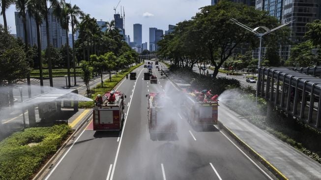 Petugas menyemprotkan cairan disinfektan di sepanjang jalan Jenderal Sudirman-MH Thamrin, Jakarta, Selasa (31/3/2020).  [ANTARA FOTO/Muhammad Adimaja]