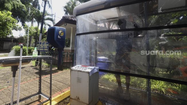 Seorang pria masuk di dalam bilik disinfektan di salah satu komplek perumahan di kawasan Jakarta Selatan, Rabu (1/4). [Suara.com/Angga Budhiyanto]