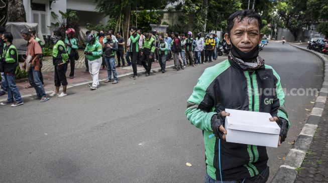 Pengemudi ojek online menunjukkan nasi kotak yang didapatkannya di kawasan Menteng, Jakarta, Jumat (3/4).  [ANTARA FOTO/Aprillio Akbar]