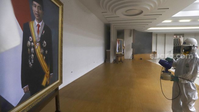 Petugas melakukan penyemprotan cairan disinfektan di gedung Komisi Pemilihan Umum (KPU) Republik Indonesia, Jakarta, Jumat (20/3). [Suara.com/Angga Budhiyanto]