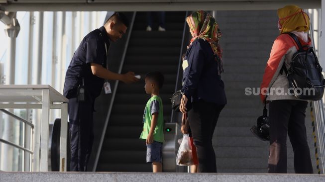 Petugas melakukan pengecekan suhu tubuh sejumlah calon penumpang sebelum memasuki Stasiun LRT Velodrome, Rawamangun, Jakarta Timur, Selasa (3/3). [Suara.com/Angga Budhiyanto] 
