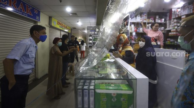 Pembeli melihat obat dari balik plastik pembatas di salah satu apotek di kawasan Pasar Baru, Jakarta, Jumat (3/4). [Suara.com/Angga Budhiyanto]