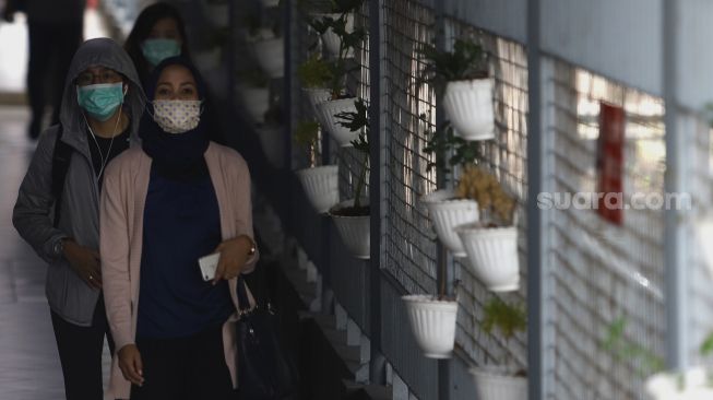 Sejumlah warga menggunakan masker melintas di kawasan Stasiun Sudirman, Jakarta, Selasa (3/3). [Suara.com/Angga Budhiyanto]