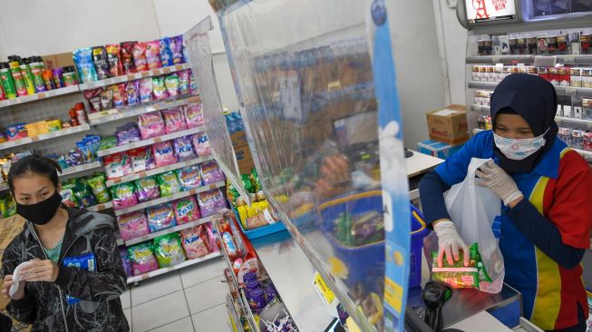 Karyawan melayani pembeli dari balik plastik pembatas di salah satu mini market di Jakarta, Sabtu (4/4).   [ANTARA FOTO/M Risyal Hidayat]