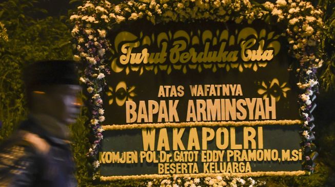 Warga melintas di depan karangan bunga ucapan bela sungkawa atas meninggalnya Wakil Jaksa Agung Arminsyah di rumah duka, Jakarta, Sabtu (4/4). [ANTARA FOTO/Muhammad Adimaja]