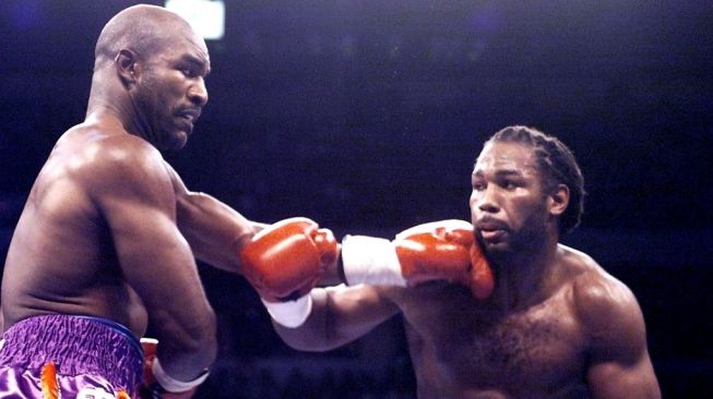 Juara dunia tinju kelas berat WBC Lennox Lewis (kanan) beradu pukulan melawan pemegang sabuk WBA dan IBF Evander Holyfield dalam duel tinju dunia di Las Vegas, Amerika Serikat, Sabtu (13/11/1999). [AFP/Jeff Haynes]