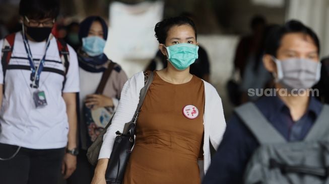 Warga menggunakan masker melintas di kawasan Stasiun Sudirman, Jakarta, Minggu (6/4). [Suara.com/Angga Budhiyanto]