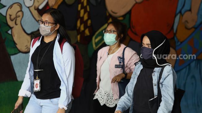Sejumlah warga menggunakan masker melintas di terowongan kawasan Stasiun Sudirman, Jakarta, Minggu (6/4). [Suara.com/Angga Budhiyanto]