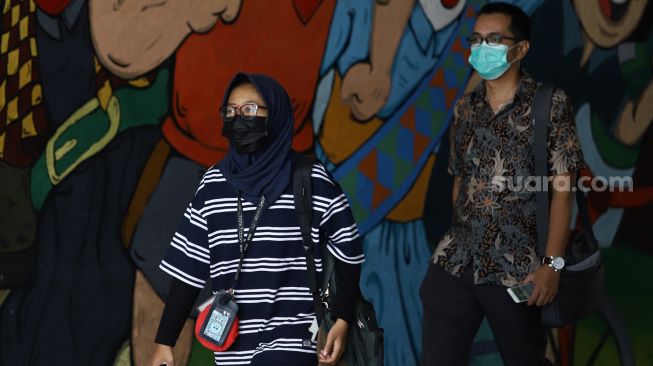 Sejumlah warga menggunakan masker melintas di lorong kawasan Stasiun Sudirman, Jakarta, Minggu (6/4). [Suara.com/Angga Budhiyanto]