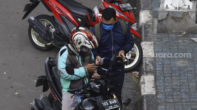 Pengemudi ojek online menurunkan penumpang di kawasan Palmerah, Jakarta, Selasa (7/4). [Suara.com/Angga Budhiyanto]  