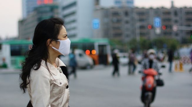 Ilustrasi seeorang perempuan pengenakan masker kain. [Shutterstock]