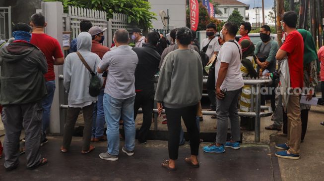 Antrean warga untuk membeli masker di sebuah pabrik di Jalan Raya Bogor, Depok, Jawa Barat, Selasa (7/4). [Suara.com/Alfian Winanto]
