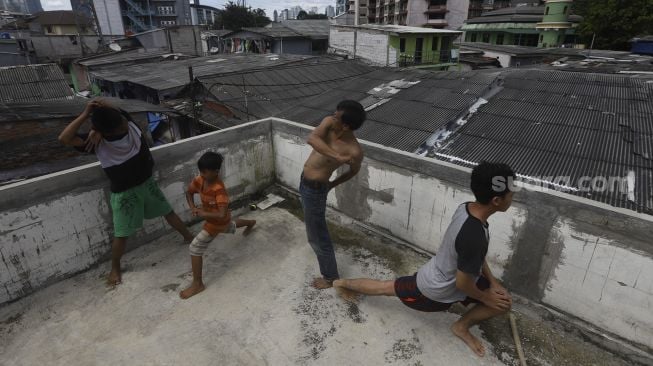 Sejumlah warga berjemur sambil melakukan olahraga kecil di balkon rumahnya di permukiman padat di kawasan Pejompongan, Jakarta, Selasa (7/4). [Suara.com/Angga Budhiyanto]