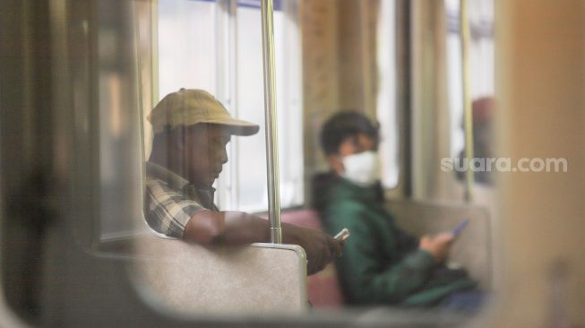 Aktivitas penumpang di dalam gerbong Commuterline, Jakarta, Rabu (8/4). [Suara.com/Alfian Winanto]
