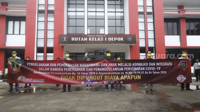 Narapidana bersiap meninggalkan Ruman Tahanan Negara (Rutan) membentangkan spanduk berisi pembebasan warga binaan usai mengikuti upacara pelepasan di Rumah Tahanan Negara (Rutan) Kelas I Depok, Jawa Barat, Kamis (9/4). [Suara.com/Angga Budhiyanto]