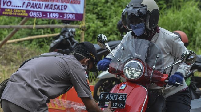 
Petugas Gugus Tugas COVID-19 menempelkan stiker pada kendaraan bermotor di Perbatasan Tasikmalaya-Ciamis, Jembatan Cirahong, Kabupaten Ciamis, Jawa Barat, Jumat (10/4). [ANTARA FOTO/Adeng Bustomi]