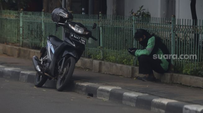 Pengendara ojek online menunggu pesanan di kawasan Kemang, Jakarta, Jumat (10/4). [Suara.com/Angga Budhiyanto] 