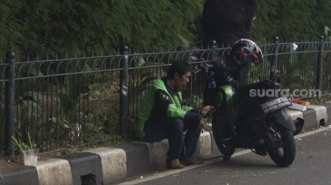 Pengendara ojek online menunggu pesanan di kawasan Senayan, Jakarta, Jumat (10/4). [Suara.com/Angga Budhiyanto] 