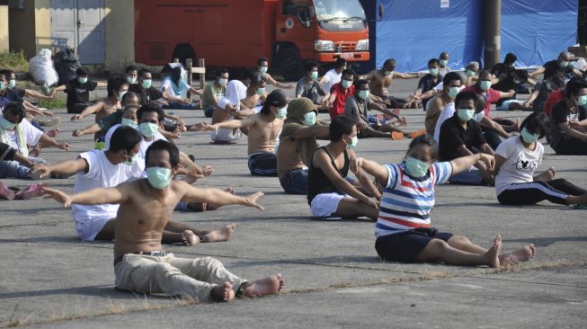 Sejumlah Tenaga Kerja Indonesia (TKI) asal Malaysia mengikuti senam dan berjemur di bawah sinar matahari saat menjalani karantina di Pangkalan Udara Militer (Lanud) Soewondo Medan, Sumatera Utara, Sabtu (11/4). [ANTARA FOTO/Septianda Perdana]