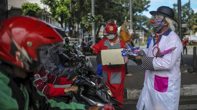 Anggota Perkumpulan Badut Jawa Barat (PBJB) membagikan masker di Pasteur, Bandung, Jawa Barat, Sabtu (11/4). [ANTARA FOTO/Raisan Al Farisi]