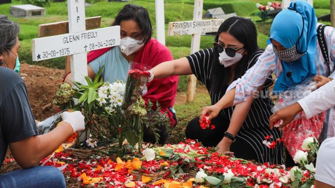 Mutia Ayu bersama kerabat menaburkan bunga di pusara musisi Glenn Fredly  di TPU Tanah Kusir, Jakarta Selatan, Minggu (12/4). [Suara.com/Alfian Winanto]