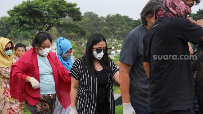 Mutia Ayu dan kerabat saat tiba di TPU Tanah Kusir, Jakarta Selatan, Minggu (12/4). [Suara.com/Alfian Winanto]