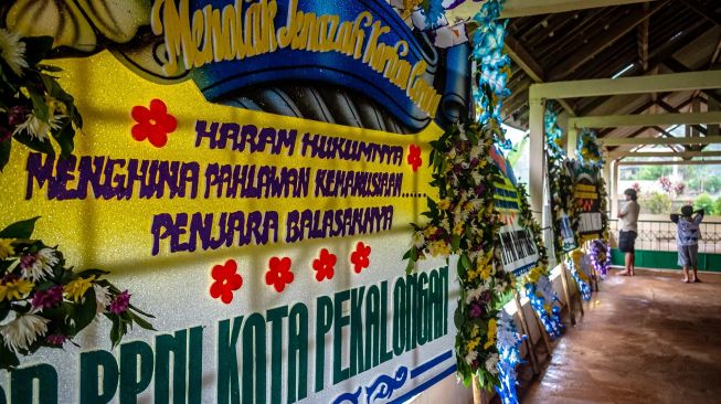 Warga menyaksikan sejumlah karangan bunga berisi protes kepada oknum warga penolak pemakaman jenazah di Tempat Pemakaman Umum (TPU) Siwarak Suwakul, Kelurahan Bandarjo, Ungaran Barat, Kabupaten Semarang, Jawa Tengah, Minggu (12/4). [ANTARA FOTO/Aji Styawan]