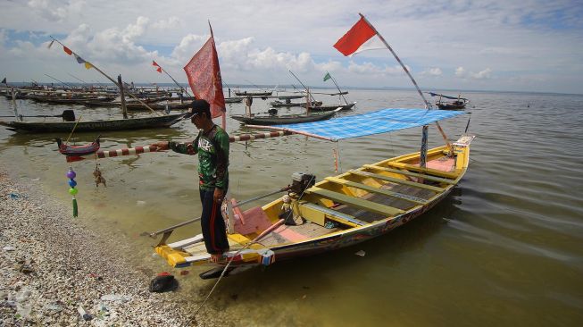 Nelayan penyedia jasa perahu wisata menunggu wisatawan di Pantai Kenjeran, Surabaya, Jawa Timur, Minggu (12/4).  [ANTARA FOTO/Moch Asim]