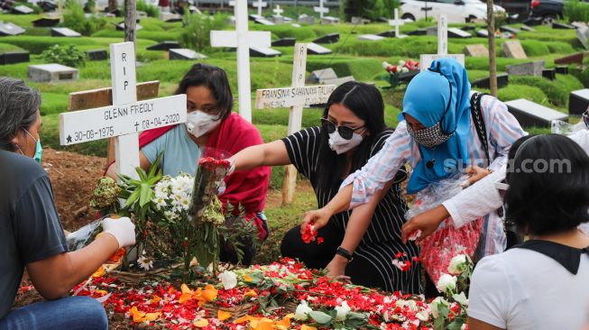 Mutia Ayu menabur bunga di pusara musisi Glenn Fredly di TPU Tanah Kusir, Jakarta Selatan, Minggu (12/4). [Suara.com/Alfian Winanto]
