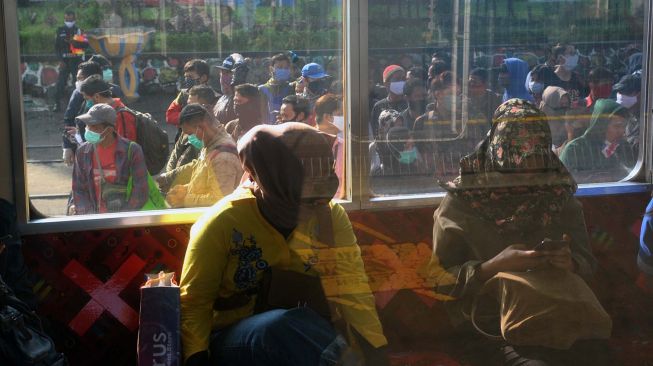 Penumpang duduk di KRL Commuter Line belatarkan penumpang yang mengantre di Stasiun Bogor, Jawa Barat, Senin (13/4). [ ANTARA FOTO/Arif Firmansyah]