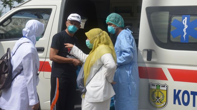 Seorang pasien positif COVID-19 (kedua kiri) yang dinyatakan sembuh bersiap menaiki mobil ambulan saat pemulangan di Rumah Sakit Zainal Abidin, Banda Aceh, Senin, (13/4). [ANTARA FOTO/Ampelsa]