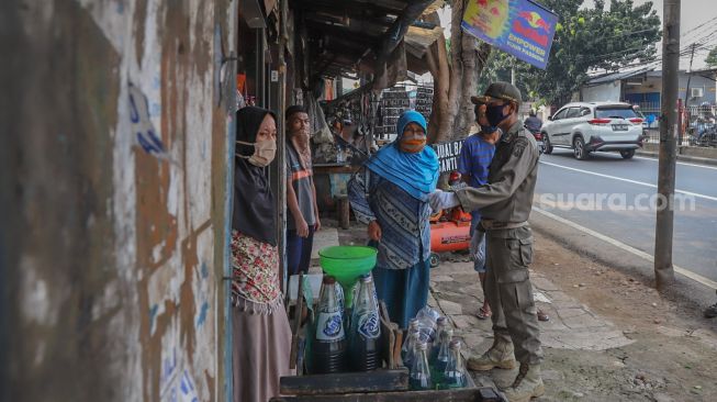 Petugas dan pemilik usaha kecil membaca bersama surat berisi himbauan dari Pemprov DKI terkait penutupan tempat usaha selama PSBB di Kramat Jati, Jakarta Timur, (13/4).  [Suara.com/Alfian Winanto]
