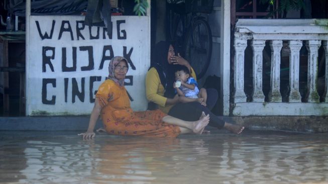 Warga bersantai di depan rumahnya yang terendam banjir di kawasan Kraton, Pasuruan, Jawa Timur, Selasa (14/4). [ANTARA FOTO/Umarul Faruq]