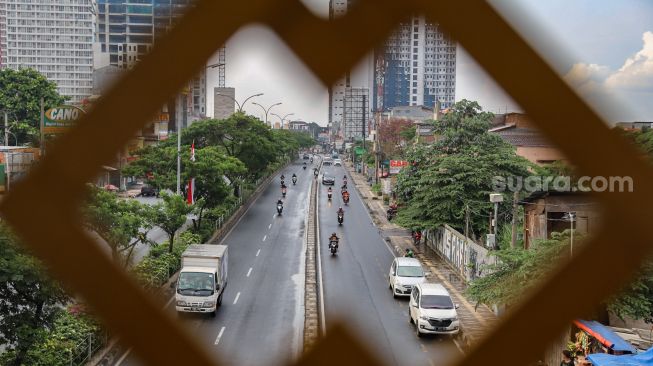 Pengendara melintas di Jalan Margonda, Depok, Jawa Barat, Selasa (14/4). [Suara.com/Alfian Winanto]