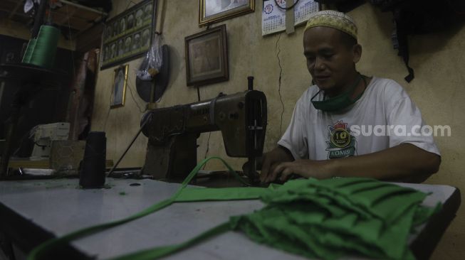 Pekerja menyelesaikan pembuatan alat pelindung diri (APD) tenaga medis dan non medis di sebuah industri rumahan, di Kawasan Manggarai, Jakarta, Rabu (15/4). [Suara.com/Angga Budhiyanto]