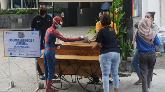 Petugas mengenakan kostum Spiderman membagikan nasi bungkus di depan Hotel Dafam, Seturan, Sleman, D.I Yogyakarta, Rabu (15/4).  [ANTARA FOTO/Andreas Fitri Atmoko]